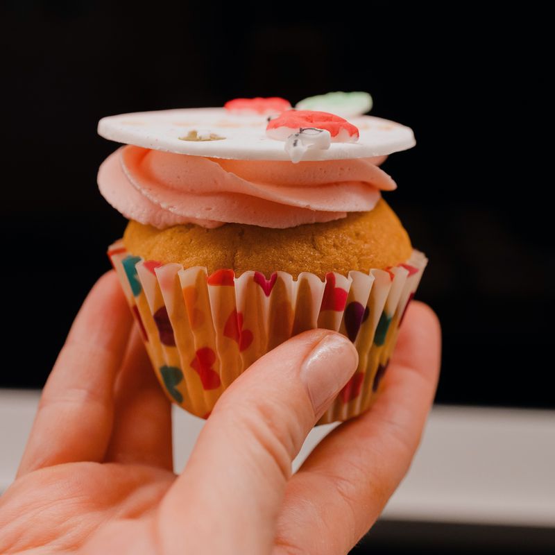 Cupcake u ruci s rozom kremom i ukrasom od fondanta